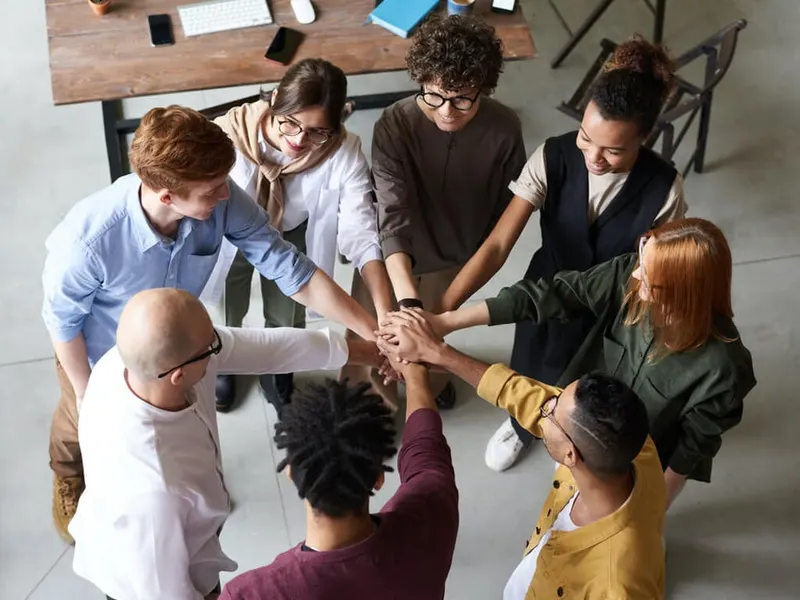 Team members joining hands over a work table